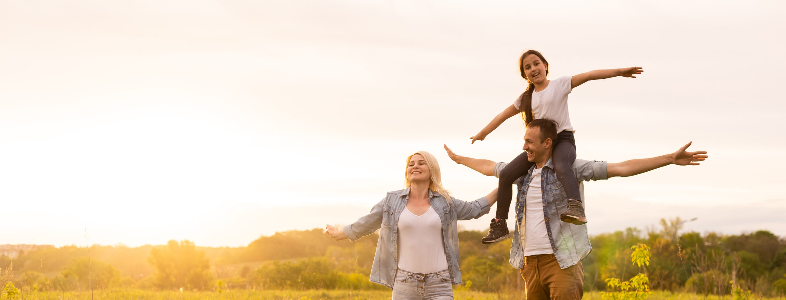 A family walking through a field at sunset