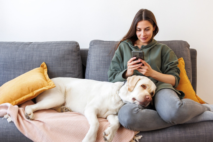 Woman banking on her phone at home with her dog