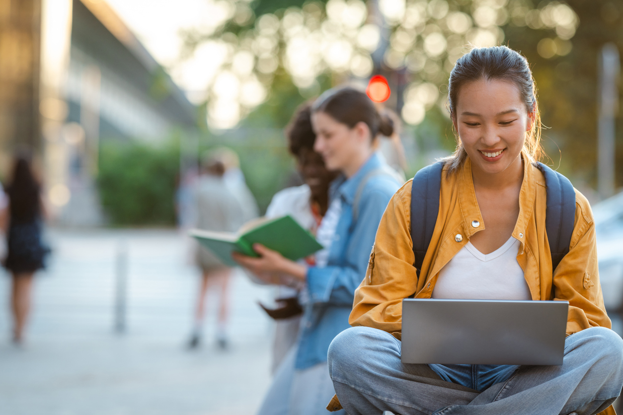 A student working on a laptop outdoors