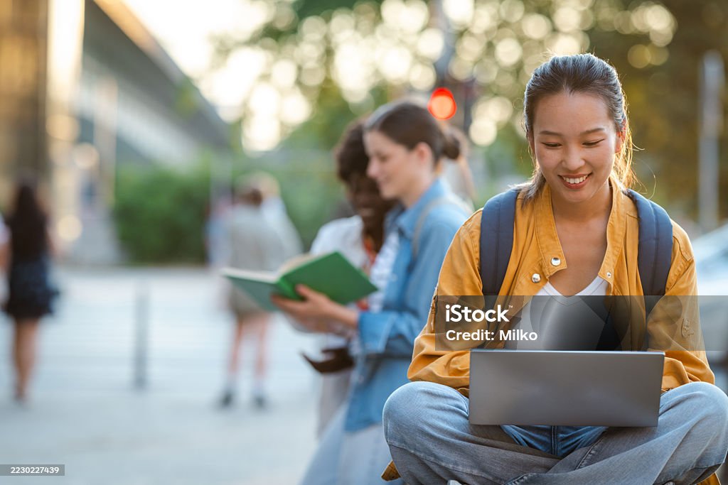 A student studying on a laptop outdoors