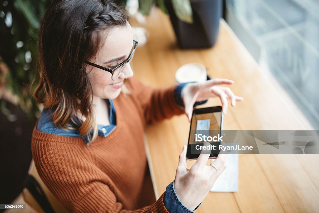 A customer depositing a check with her phone at a cafe